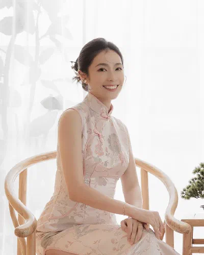 Li Han Chen 坐在薄紗窗簾旁的木椅上，面帶微笑